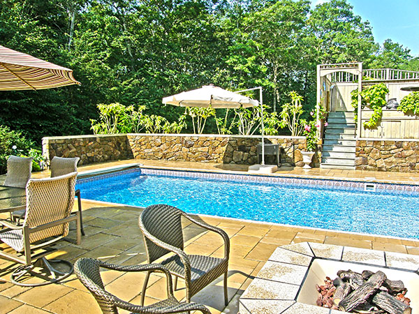 Pool side patio enhanced with rock walls, patio pavers, and a fire pit.