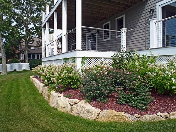 A Cape Cod home landscaped with raised plant beds around the foundation.
