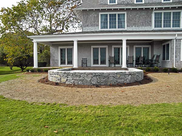 Cape Cod waterfront home with a curved rock patio space.